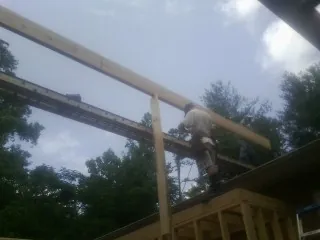 Carpenter setting a ridge beam over a new addition frame — Ice Dam Removal by Roofing Brothers in Wixom