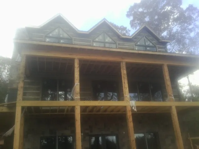 Dormers and porch framing on a large log home under construction — Roof Coating work by our crew in Wixom
