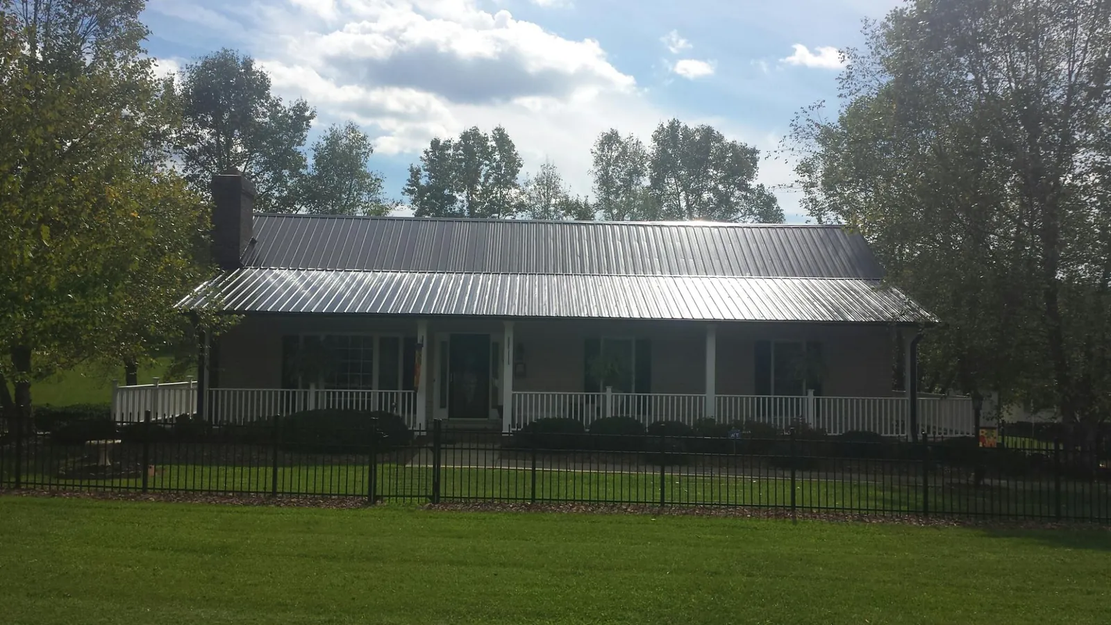 Gray metal roof on a brick ranch with a full width front porch — Gutter Guard Installation work by our crew in Wixom