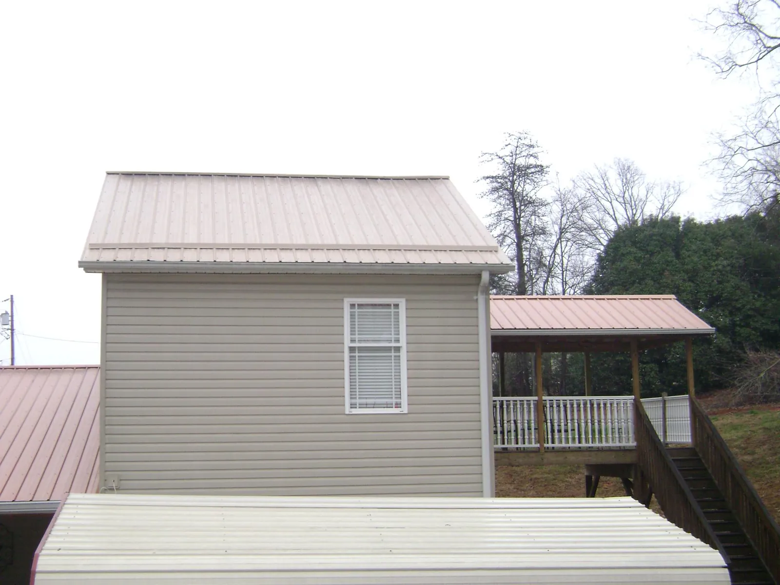 Tan metal roofs on a two story addition and attached porch, from a Roof Replacement job in Wixom